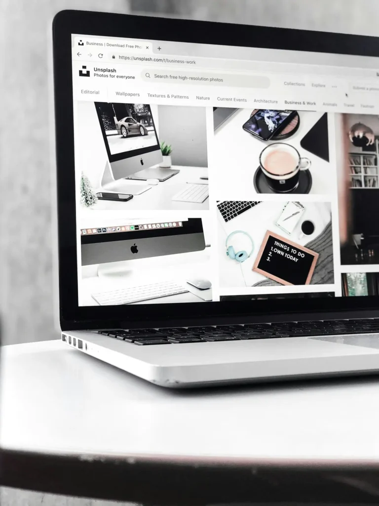 MacBook zeigt die Unsplash-Bilderdatenbank mit der Kategorie Business und Work und zahlreichen professionellen Business-Fotos – Ressource für hochwertige lizenzfreie Bilder in der Website-Erstellung