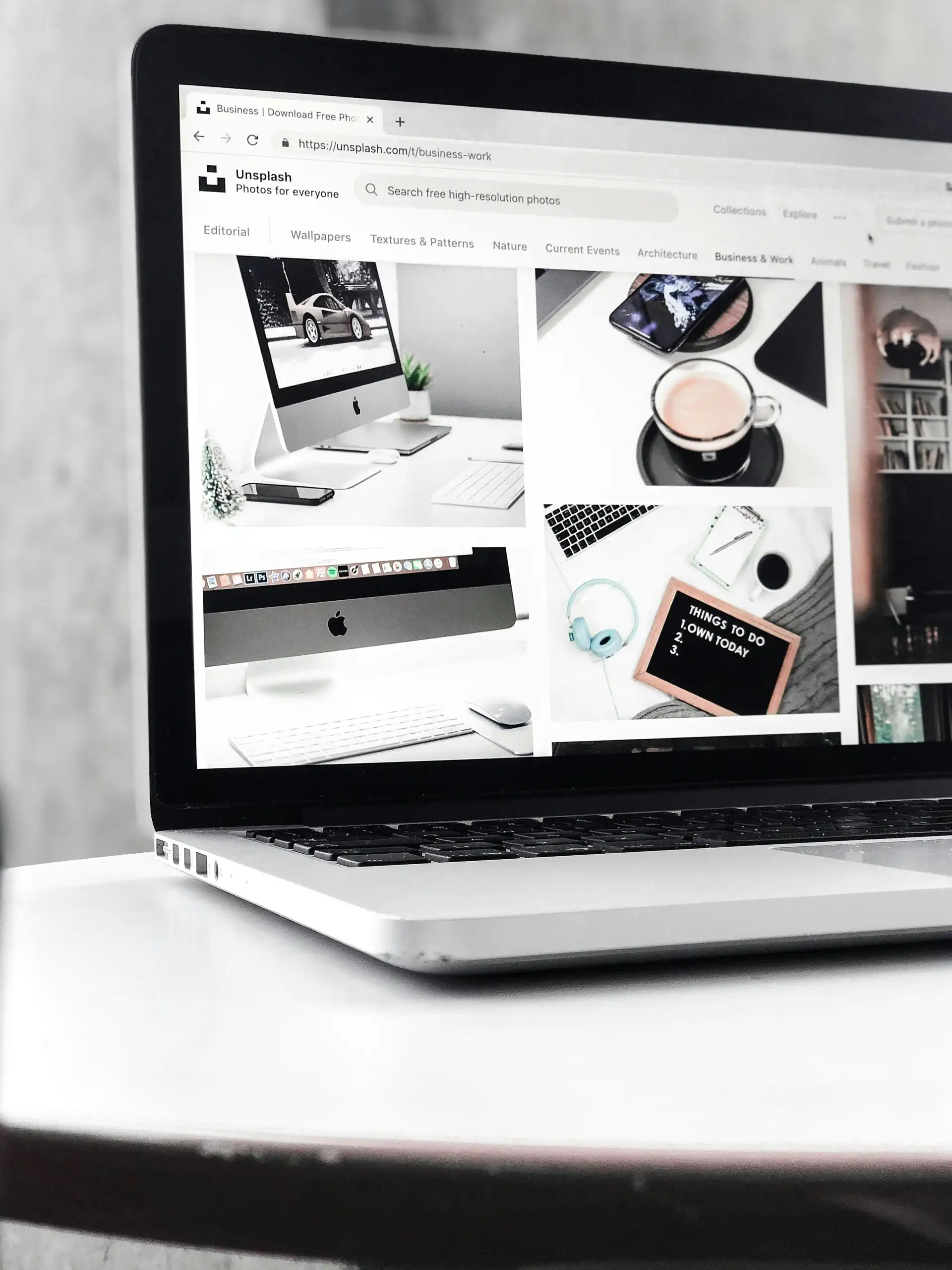 MacBook zeigt die Unsplash-Bilderdatenbank mit der Kategorie Business und Work und zahlreichen professionellen Business-Fotos – Ressource für hochwertige lizenzfreie Bilder in der Website-Erstellung